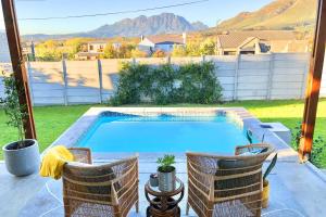 a swimming pool in a yard with two chairs at Cape Winelands Mountain View Getaway in Dalsig