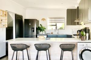 a kitchen with a counter and three chairs in it at Cape Winelands Mountain View Getaway in Dalsig