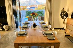 a wooden table with chairs and plates and flowers on it at Cape Winelands Mountain View Getaway in Dalsig