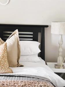 a bed with white pillows and a lamp on a table at 29 Village Place in Gaborone