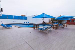 a swimming pool with blue umbrellas and tables and chairs at Hotel el Silencio in Bombiso