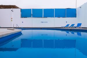 a swimming pool with blue water and blue chairs at Hotel el Silencio in Bombiso