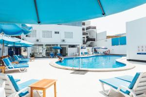 a swimming pool with blue chairs and people in it at Hotel el Silencio in Bombiso
