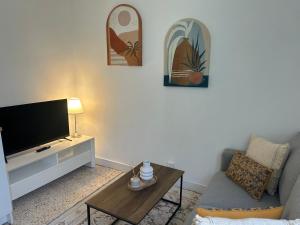 a living room with a tv and a couch and a table at Le Petit Rocher in Pierrelatte