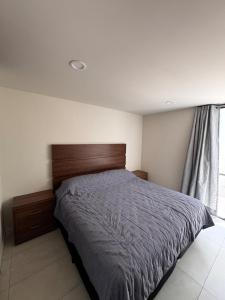 a bedroom with a bed with a wooden headboard and a window at Refugio urbano Saori in Guadalajara