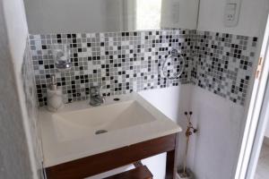 a bathroom with a sink and a tiled wall at Hostería La Cascada in Alpa Corral +12 photos