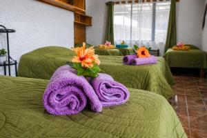 a group of four green beds with towels on them at Cabañas & Hostal Tojika in Hanga Roa +116 photos