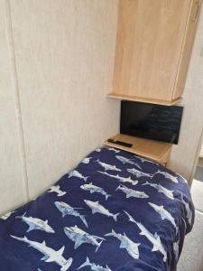 a bed in a room with a blue comforter with white sharks at BELLESVIEW Clarach Bay in Aberystwyth