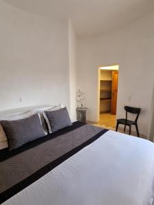 a bedroom with a large white bed with a chair at Casa 13 - Refúgio Salinas in Vila do Porto