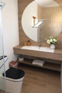 a bathroom with a round mirror and a sink at Casa 13 - Refúgio Salinas in Vila do Porto +29 photos