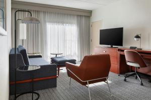 a hotel room with a couch and a television at Courtyard by Marriott Boston Norwood/Canton in Norwood