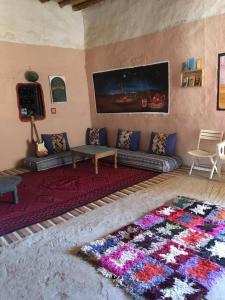 a living room with a couch and a rug at Merzouga Hostel in Merzouga
