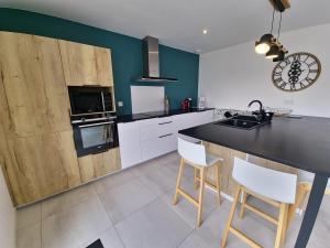 a kitchen with white cabinets and a black counter top at 300m de la mer, villa moderne spacieuse 6-12 pers à Trévignon in Trégunc