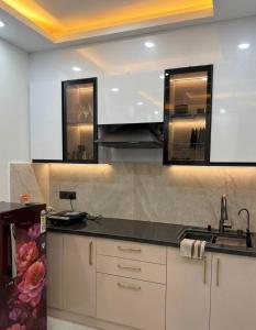 a kitchen with white cabinets and a black counter top at Skyline suites in Noida