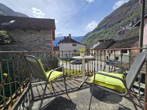 a balcony with chairs and a table with mountains in the background at Garni Cà Stella in Bignasco