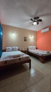 a bedroom with two beds and a ceiling fan at Ometepe House in Moyogalpa