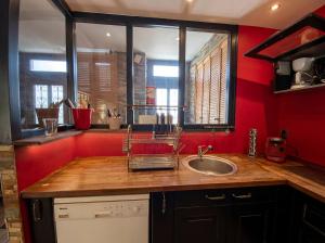a bathroom with a sink and a red wall at Le loft de l'entrepote in Argenton-sur-Creuse +3 photos