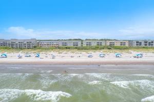 a beach with a group of people and umbrellas at Captains Choice by Oak Island Accommodations in Caswell Beach
