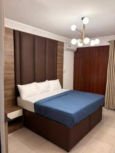 a bedroom with a large bed with a blue blanket at OD-VICK'S PLUSH STUDIOS, Utako in Abuja