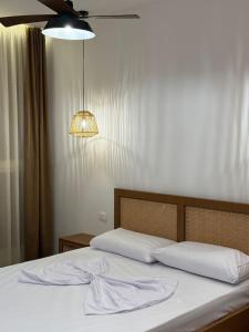 a bedroom with a bed with white sheets and a light at Palm Paradise Apartaments in Golem