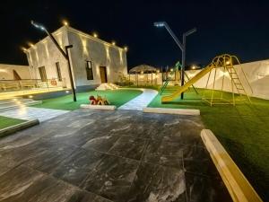 a playground with a slide in a yard at night at Welcome to Chalet Bonsiana! in Jeddah