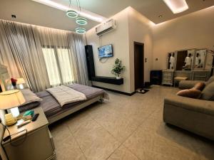 a bedroom with a bed and a couch and a tv at Welcome to Chalet Bonsiana! in Jeddah