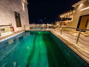 a swimming pool with green water at night at Welcome to Chalet Bonsiana! in Jeddah