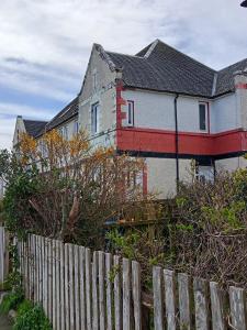 a house with a fence in front of it at Cozy Homestay in Rothesay