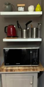 a black microwave on a counter with shelves at Studio tout équipé, emplacement idéal in Saint-Raphaël