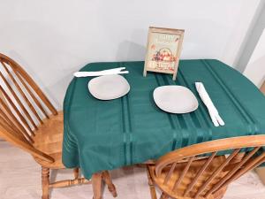 a green table with plates and a book on it at Ideal Bachelor Suite For Couples in Aurora in Aurora +2 photos