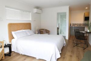 a bedroom with a large white bed and a kitchen at Coastal Calm Papamoa in Tauranga +2 photos