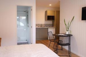 a bedroom with a bed and a table and a kitchen at Coastal Calm Papamoa in Tauranga