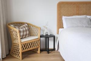 a bedroom with a bed and a chair and a table at Coastal Calm Papamoa in Tauranga