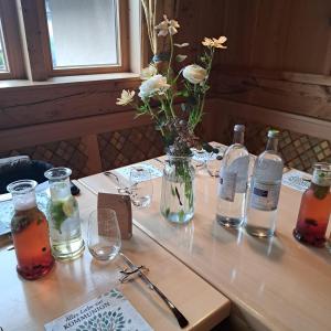 a table with bottles and glasses and a vase with flowers at Brend Hotel und Gasthof in Furtwangen