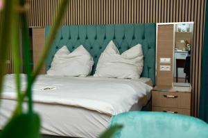 ein Bett mit weißen Kissen und einem grünen Kopfteil in der Unterkunft Mersa Hotel in Backnang