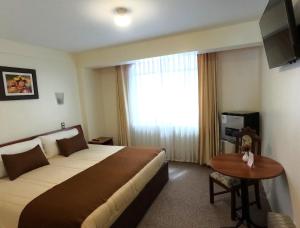a hotel room with a large bed and a window at Hotel Munay Tambo in Puno