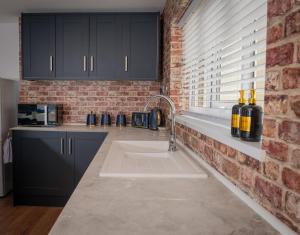 a kitchen with a sink and a brick wall at Easterly Sleeps in Lowestoft +24 photos