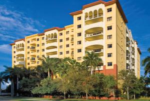 a tall building with palm trees in front of it at Club Wyndham Sea Gardens in Pompano Beach