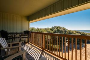 a balcony with a table and chairs and a view of the ocean at Castaway by Oak Island Accommodations in Caswell Beach