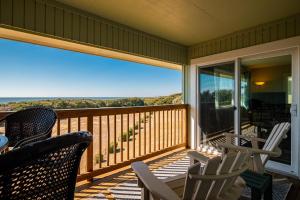 a porch with chairs and a view of the ocean at Castaway by Oak Island Accommodations in Caswell Beach