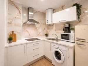 a kitchen with white cabinets and a washer and dryer at Ohana Urban Málaga Centro in Málaga