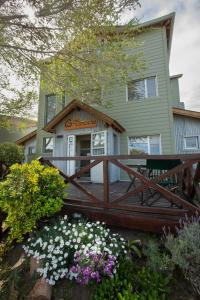 a house with a wooden deck and flowers at Del Nomade Hosteria Ecologica in Puerto Pirámides