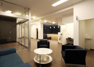 a room with couches and a table and chairs at Smile Hotel Sendai Tagajyo in Tagajo