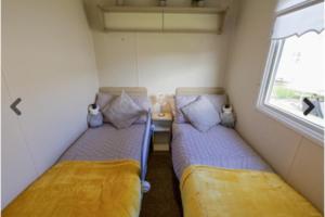 two beds in a small room with a window at Lyons Robinhood - 3 bedrooms in Rhyl +6 photos