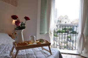 マテーラにあるRoseus La Casa Vacanze nei Sassiのベッド1台とテーブル(食べ物付)が備わる客室です。