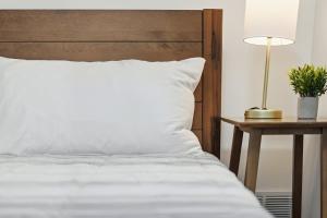 a bed with white sheets and a table with a lamp at Pittsburgh Millvale A Bright & Cozy Private Bedroom with Shared Bathroom in Pittsburgh