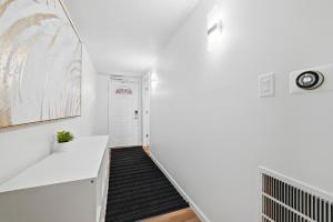a hallway with white walls and a staircase with a black rug at Pittsburgh Millvale A Bright & Cozy Private Bedroom with Shared Bathroom in Pittsburgh