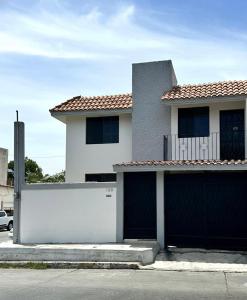 a white house with a fence and a garage at Casa Moderna, Ubicación Estrategjca in Cedro