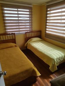 two beds in a room with two windows at Hospedaje LARRAIN in Valparaíso +13 photos