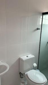 a white bathroom with a toilet and a sink at Apto lateral mar in Porto Belo